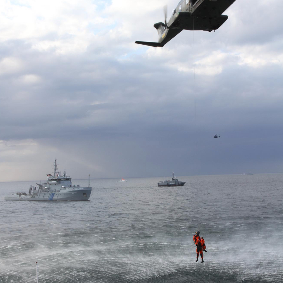 Man hanging from a helicopter above the sea