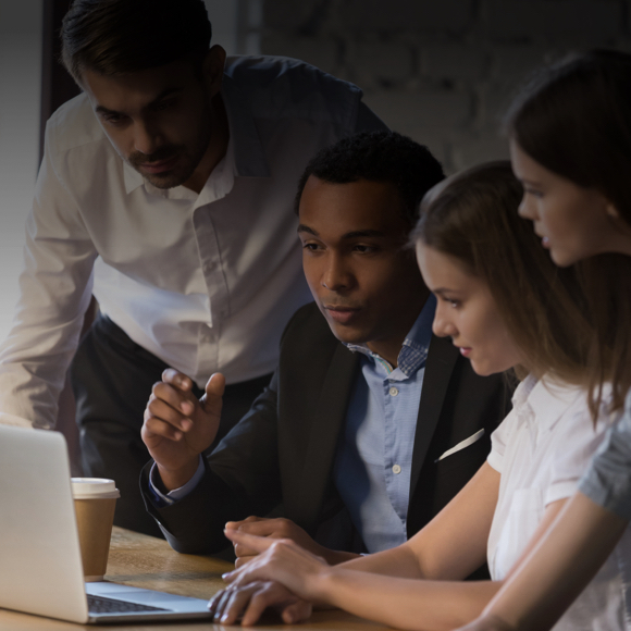 Four employees sitting together in front of a laptop