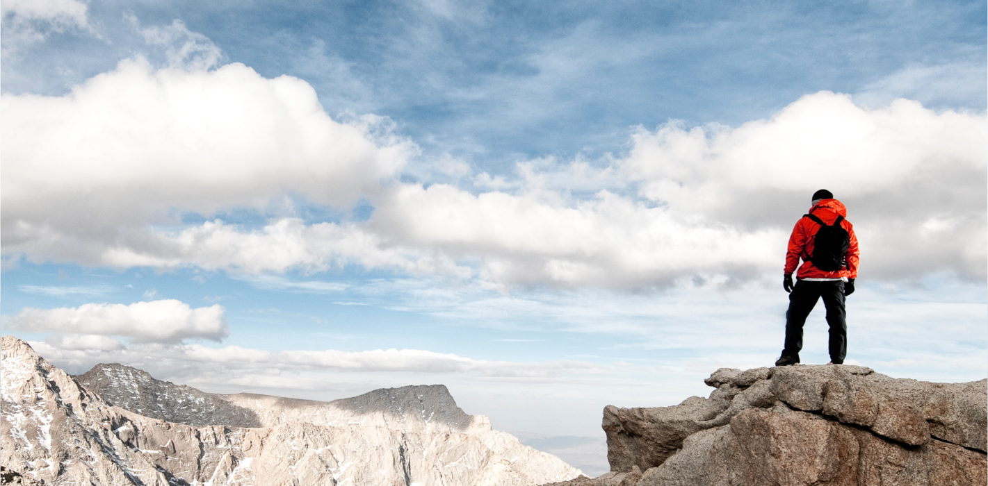 Man with a red jacket on a stone's peak