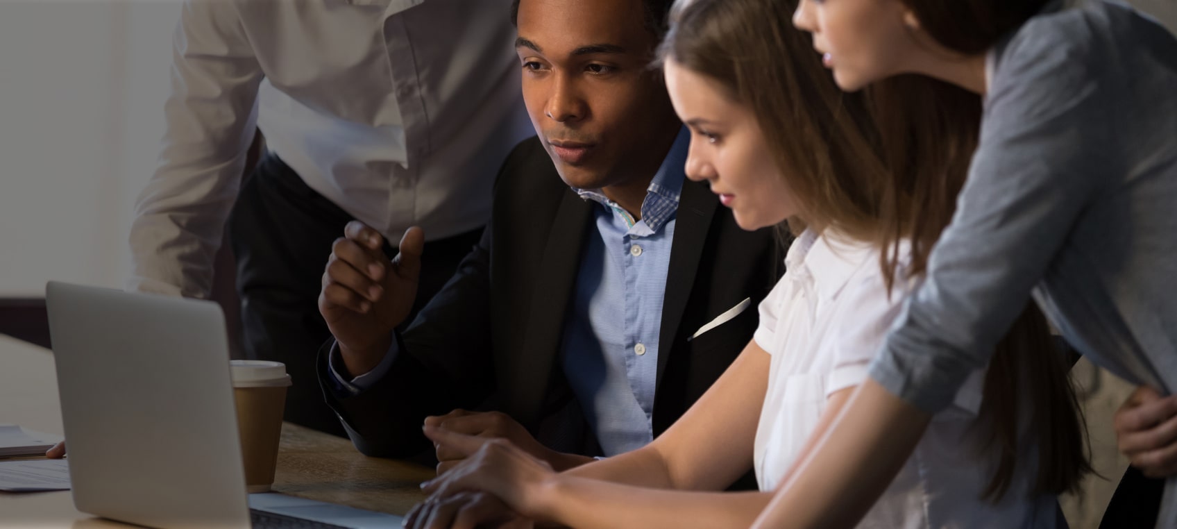 Four employees sitting together in front of a laptop